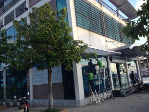 Đội ngũ nhân viên Nhà Sạch 24h đang thực hiện dịch vụ lau kính Cẩm Phả cho tòa nhà cao tầng bằng phương pháp đu dây an toàn.