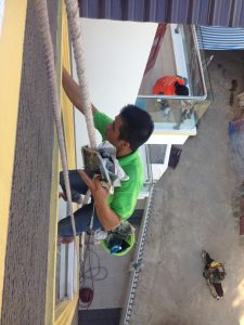 Kỹ thuật viên đu dây vệ sinh kính mặt ngoài tòa nhà - Một quy trình quan trọng trong dịch vụ lau kính Cẩm Phả.